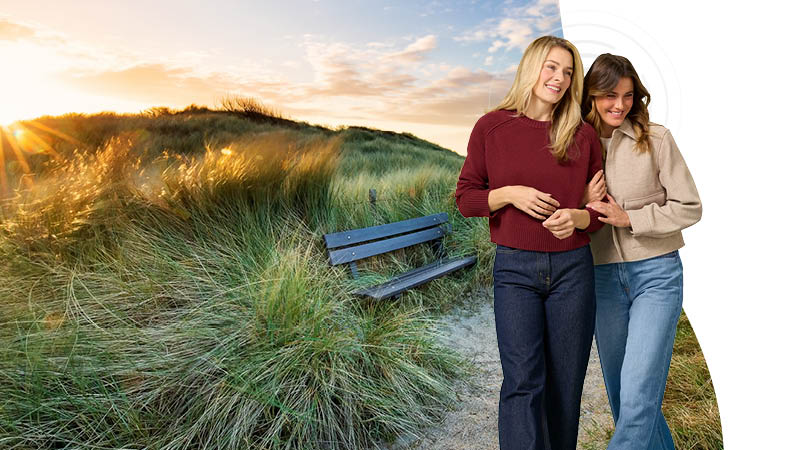 Two women talking and walking along a seaside path