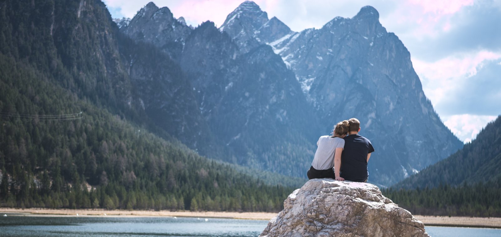 Un couple assis sur un rocher regardant un lac et les montagnes. Apprécier les sons de la nature. Un couple assis sur un rocher regardant un lac et les montagnes. Apprécier les sons de la nature.